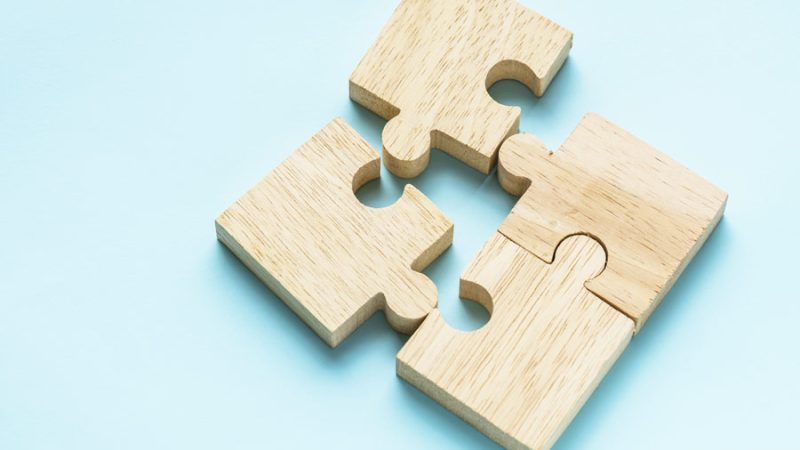 4 wooden puzzle pieces on a light blue background